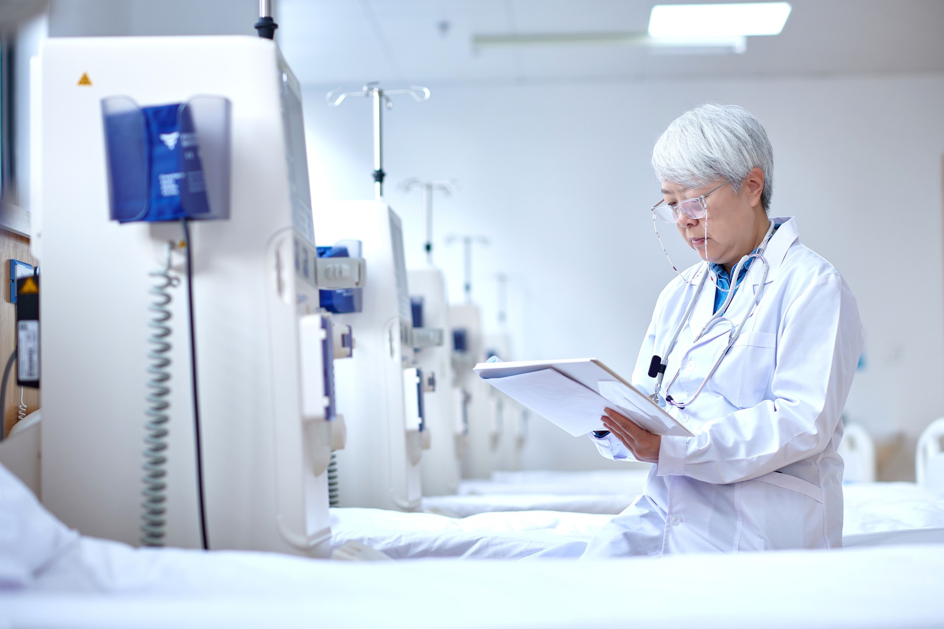 Asian Senior Doctor Checking Data at Hemodialysis Room